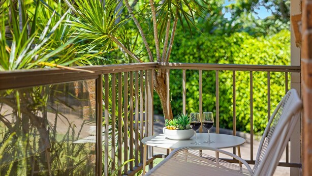 A balcony with a table and chairs, a potted plant, and a glass of red wine. - Shelly Cove Apartment 12 - aircon, pool, beach across road (Port Macquarie)