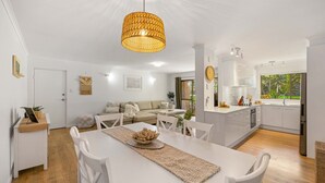 A modern kitchen with white cabinets, a built-in oven, and a window with a view of greenery. - Shelly Cove Apartment 12 - aircon, pool, beach across road (Port Macquarie)