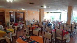 Un comedor con varias mesas y sillas, algunas con manteles de colores.