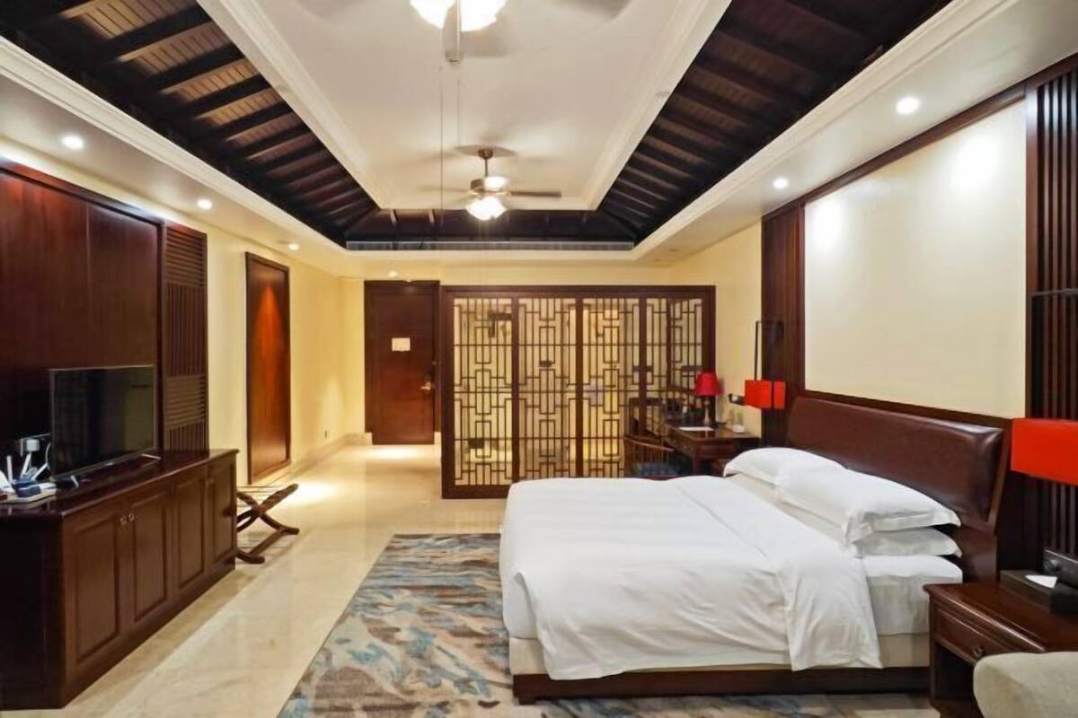 A hotel room with a bed, a TV, a desk, and a wardrobe.
