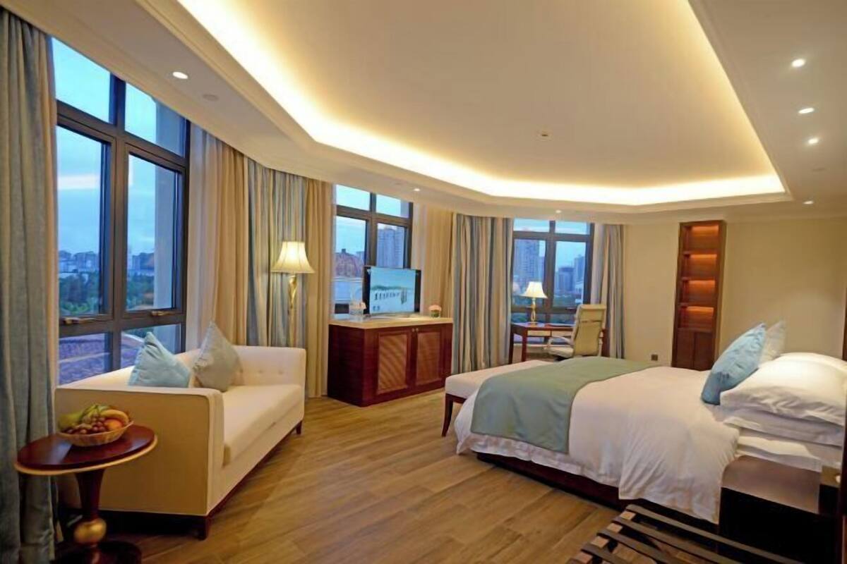 A hotel room with a bed, a sofa, a desk, and a TV.
