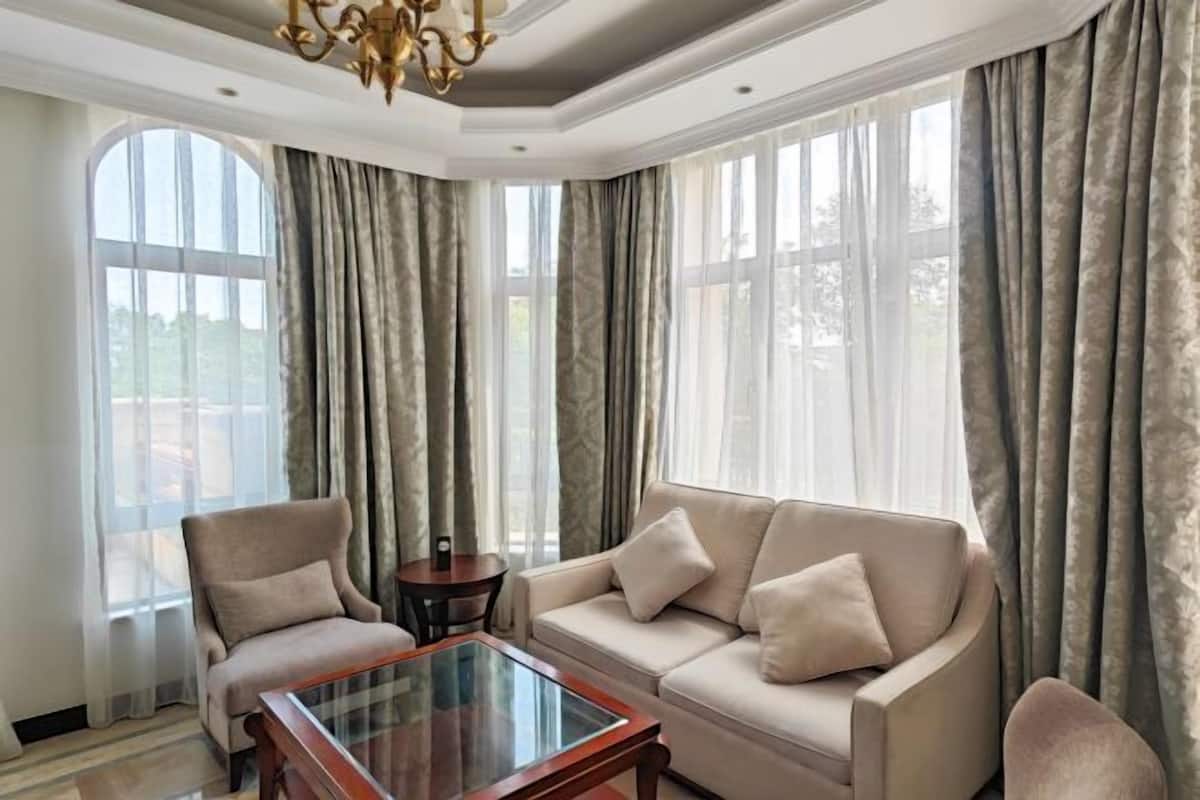 A living room with a sofa, armchair, and a glass-top coffee table.