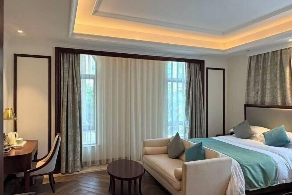 A hotel room with a bed, a sofa, a small table, and a desk with a chair.