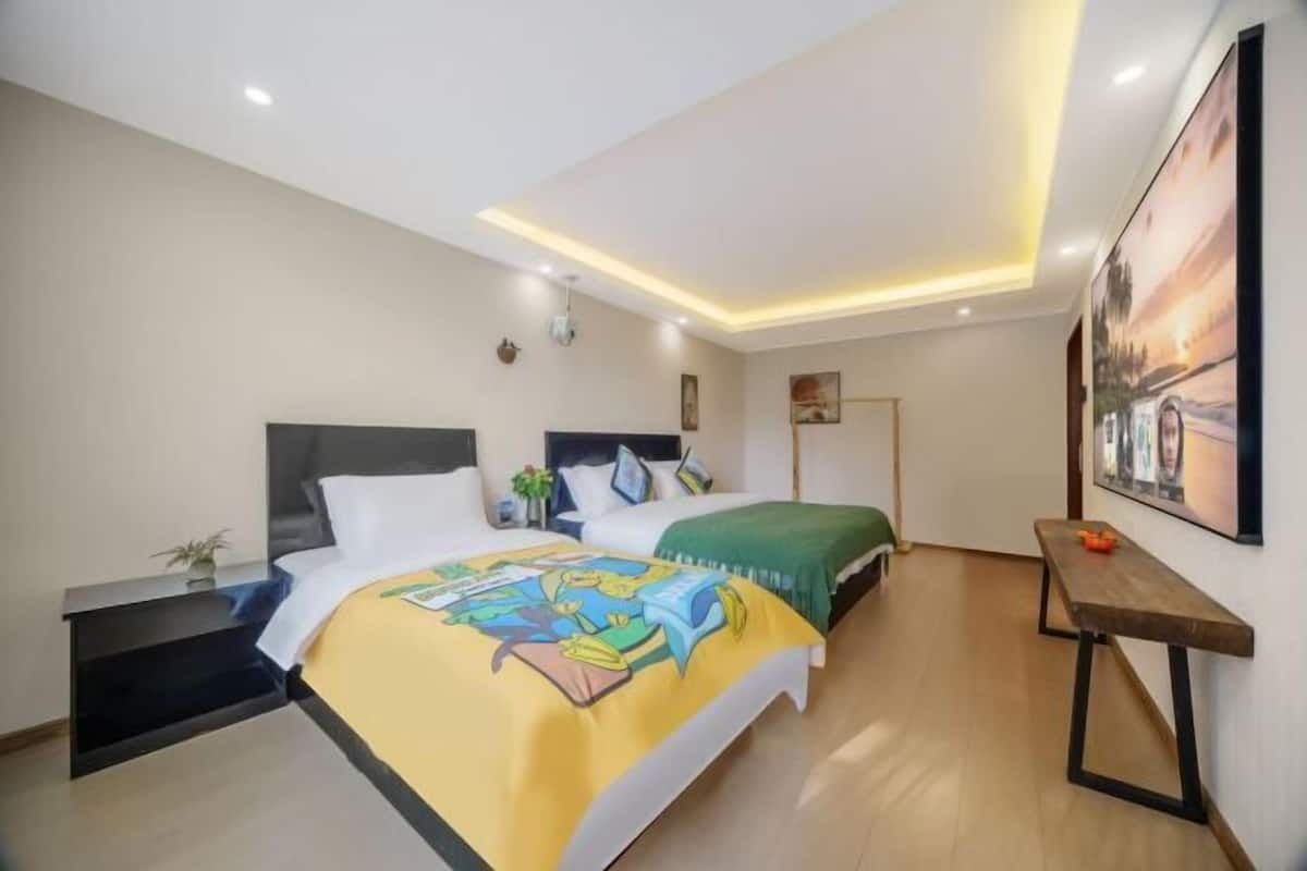 A modern hotel room with a large bed, bedside tables, a bench, and a painting on the wall.