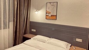 Ein Hotelzimmer mit einem Bett, einem Nachttisch, einer Hängelampe und einem Bild an der Wand.