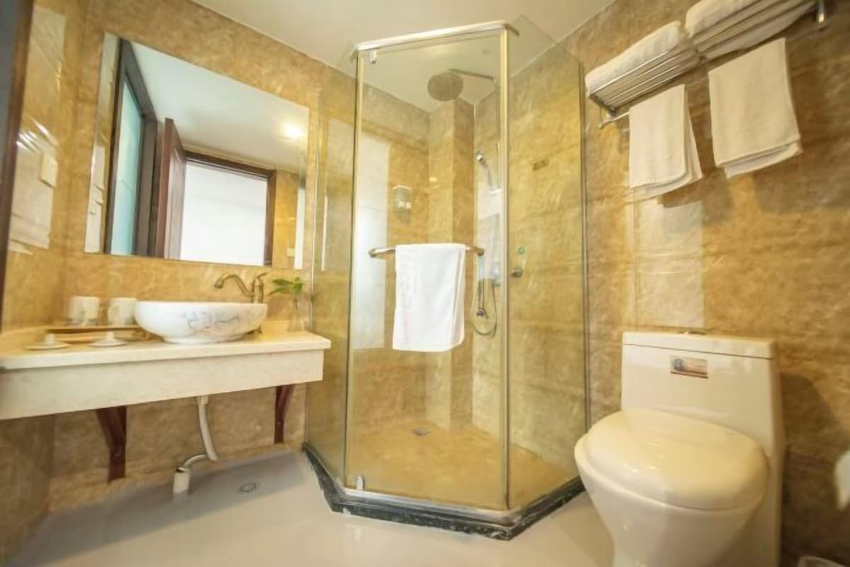 A bathroom with a glass-enclosed shower, a white sink with a bowl, and a toilet.