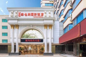 A hotel entrance with a large arched doorway, columns, and a sign with Chinese characters.