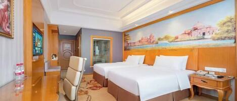 A hotel room with two beds, a desk, and a chair.