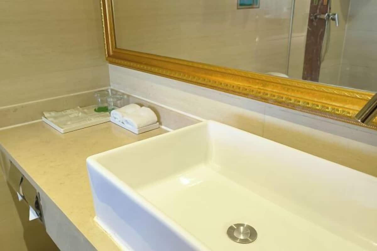 A bathroom with a white sink, a mirror with a gold frame, and toiletries on the counter.
