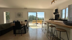 A modern kitchen with a bar area, large windows, and a dining space with a view. - House with breathtaking views of the Luberon (Caseneuve)