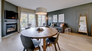 A modern living room with a fireplace, a round dining table, and a sofa. - E202-Condo ski in ski out / vélo in vélo out (Bromont)