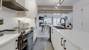 A modern kitchen with white cabinetry, stainless steel appliances, and a central island.