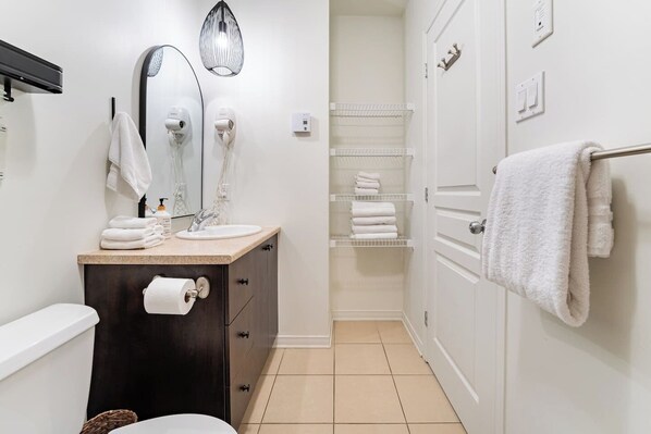 A modern bathroom with a dark wooden vanity, a white sink, and a towel rack.