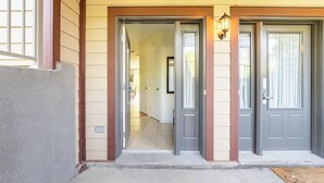 Une entrée avec deux portes grises, un couloir et un luminaire placé au-dessus des portes.