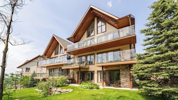 Une maison à deux étages dotée d’un balcon, de fondations en pierre et d’une pelouse bien entretenue.