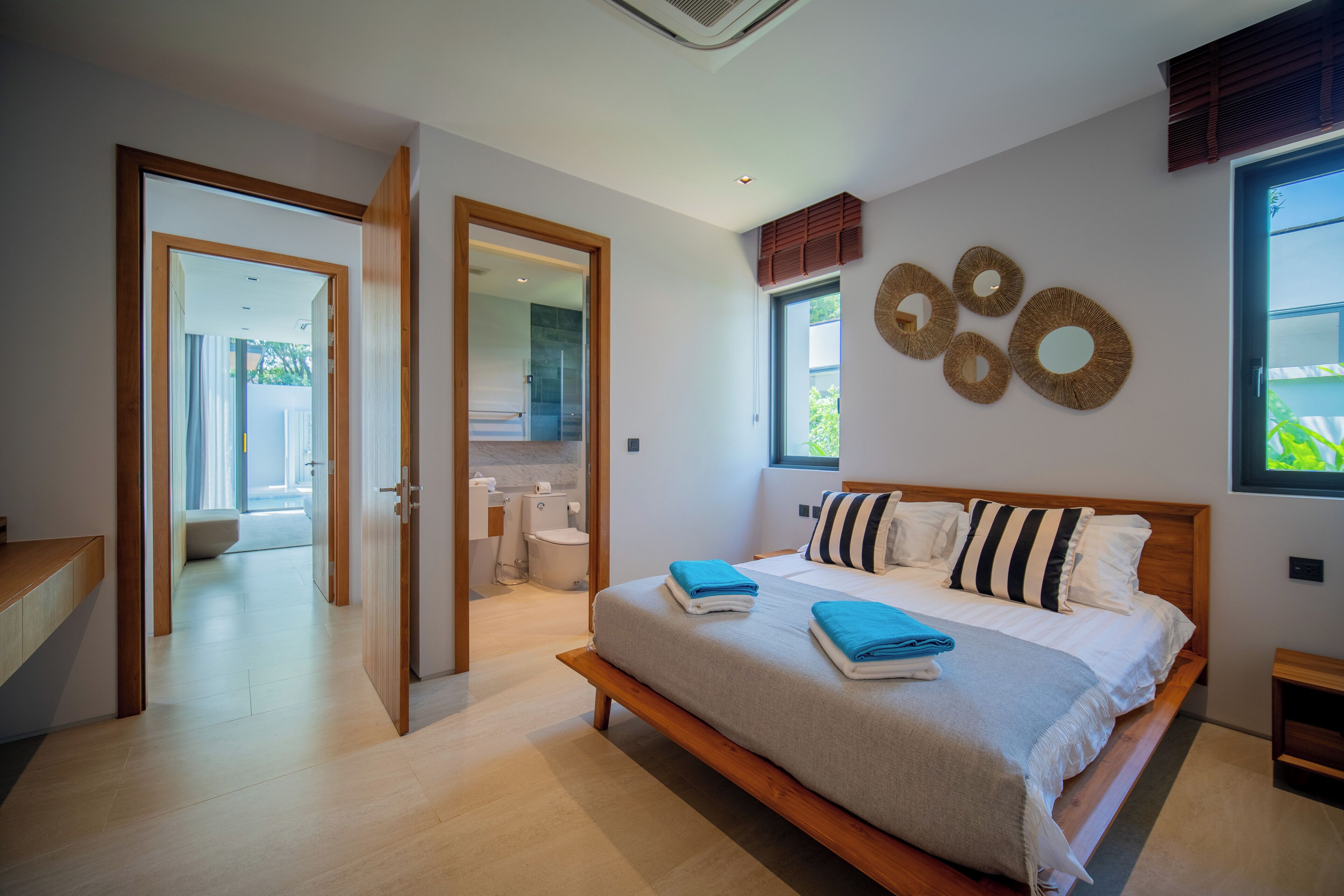 Een moderne slaapkamer met een groot bed, houten hoofdeinde en uitzicht op de omgeving.