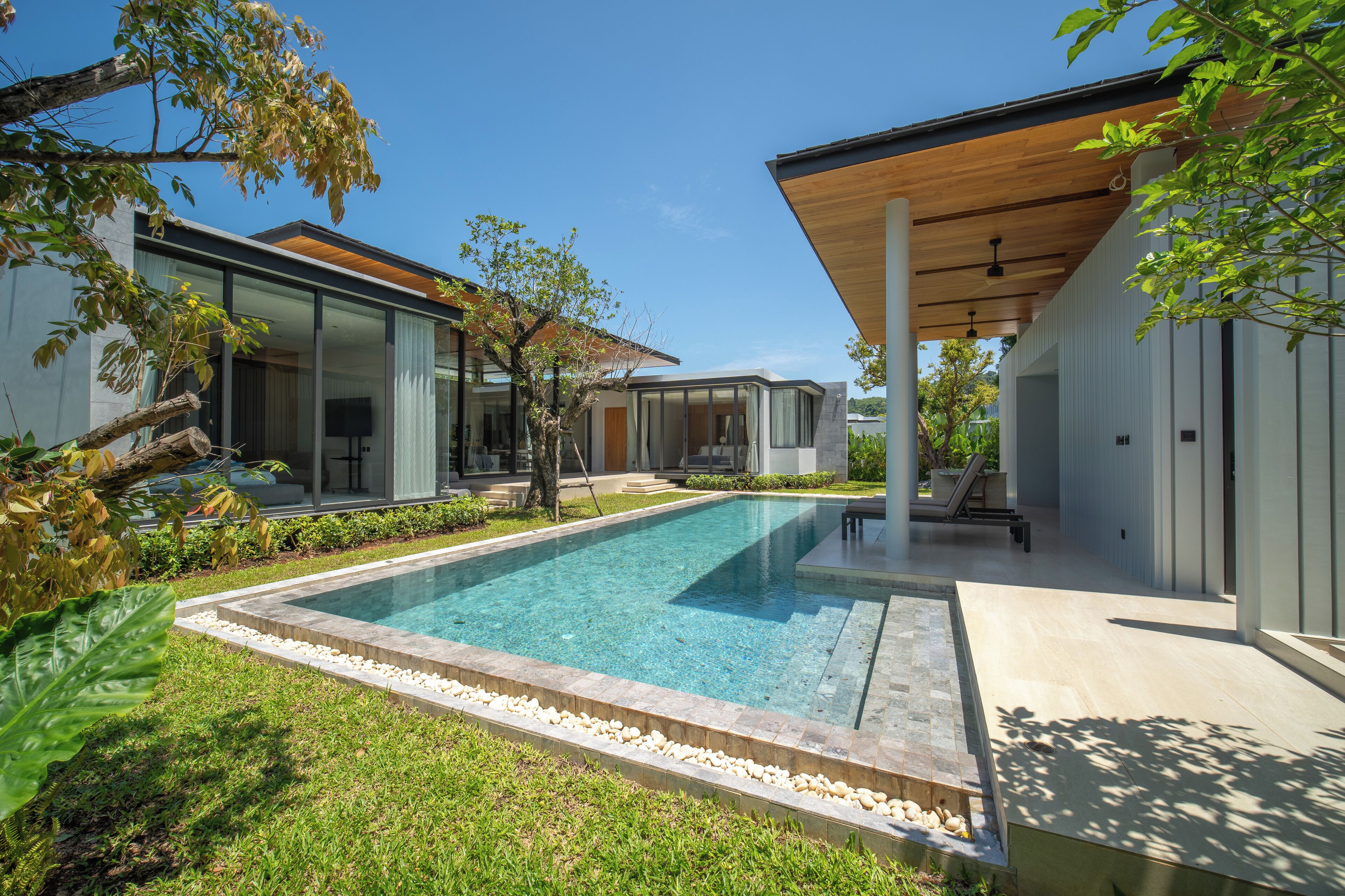 A modern house with a swimming pool, large windows, and a covered patio area.