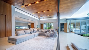 A spacious living area with a large sectional sofa, a coffee table, and a view of the outdoors through large windows.