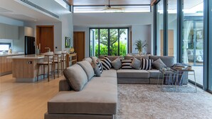 A modern living room with a large sectional sofa, a dining area, and a kitchen with a bar.