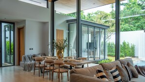 A modern living room with a dining area, large windows, and a view of the outdoors.