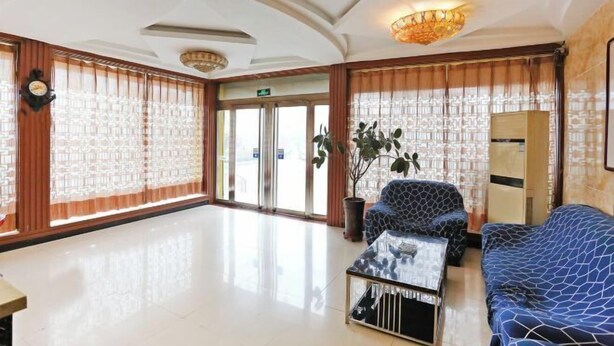 A lobby with a reception desk, patterned sofas, a coffee table, and a large plant. - huating hotel (Zhao County)