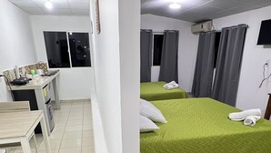 Habitación de hotel con dos camas, una mesita y un ventanal con cortinas.