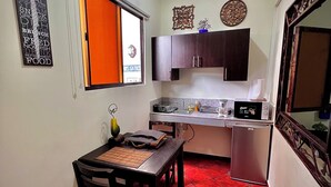 Cocina compacta con comedor, que incluye un refrigerador pequeño, un microondas y un lavabo.