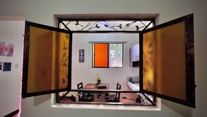 Una habitación con zona de comedor, una ventana con persiana naranja y aire acondicionado instalado en la pared.