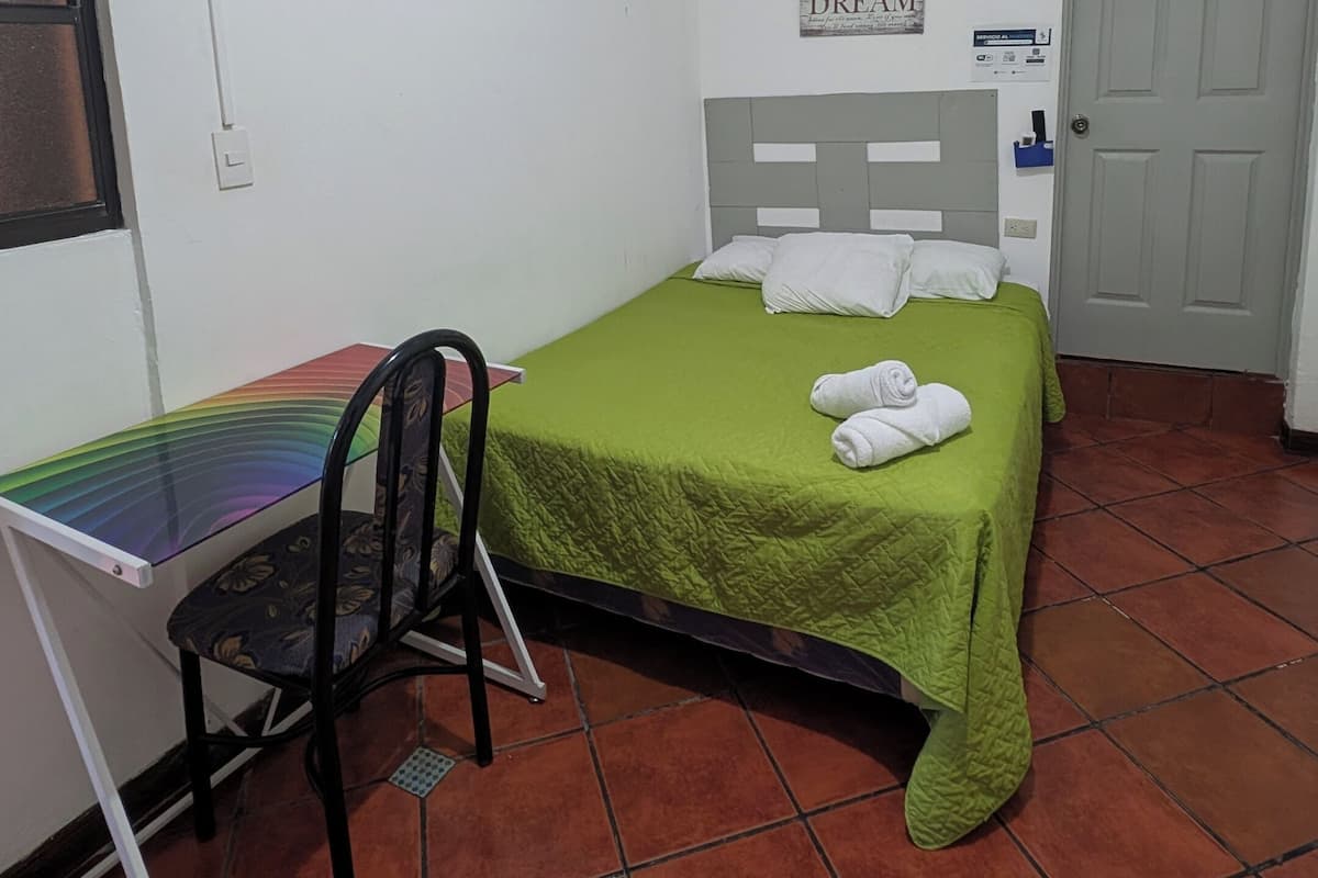 Una habitación pequeña y limpia con una cama, un escritorio y una silla.