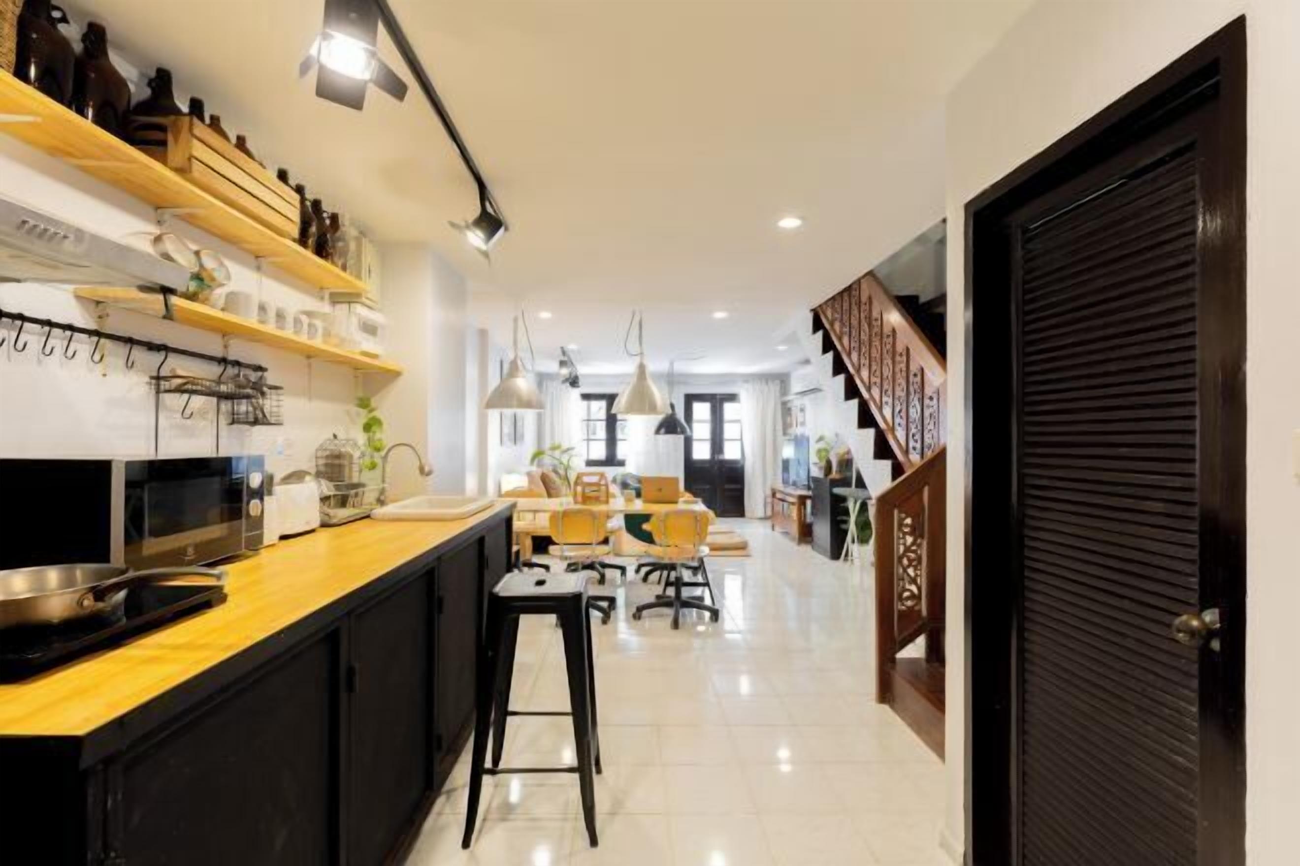 Een moderne keuken met een centraal eiland, houten planken en hangende lampen.