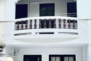A white building with a balcony featuring a wooden balustrade. - Ombra House No26 (Chiang Mai)