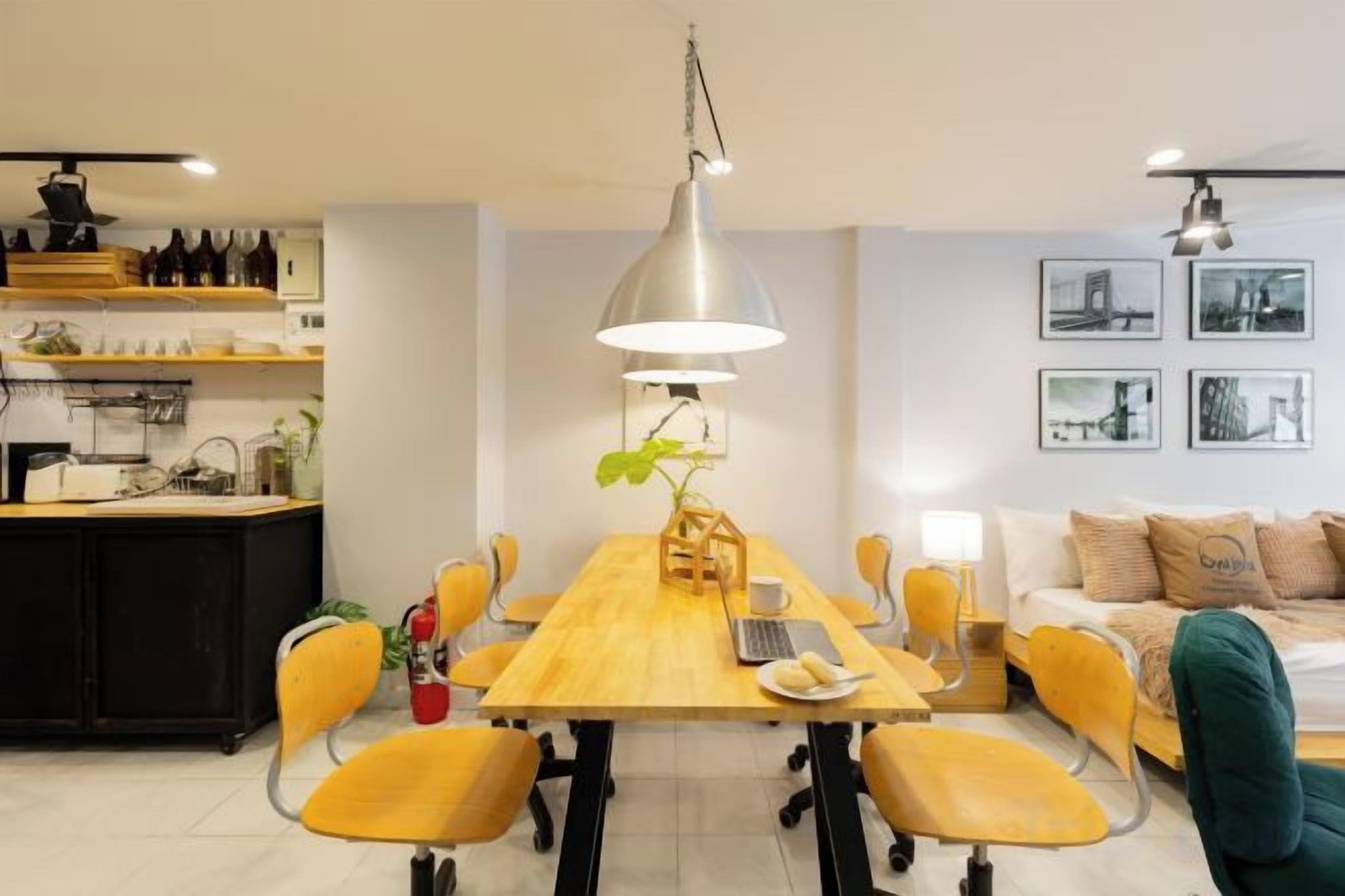 Une cuisine moderne avec un coin repas, comprenant une table en bois, des chaises jaunes et un luminaire suspendu.