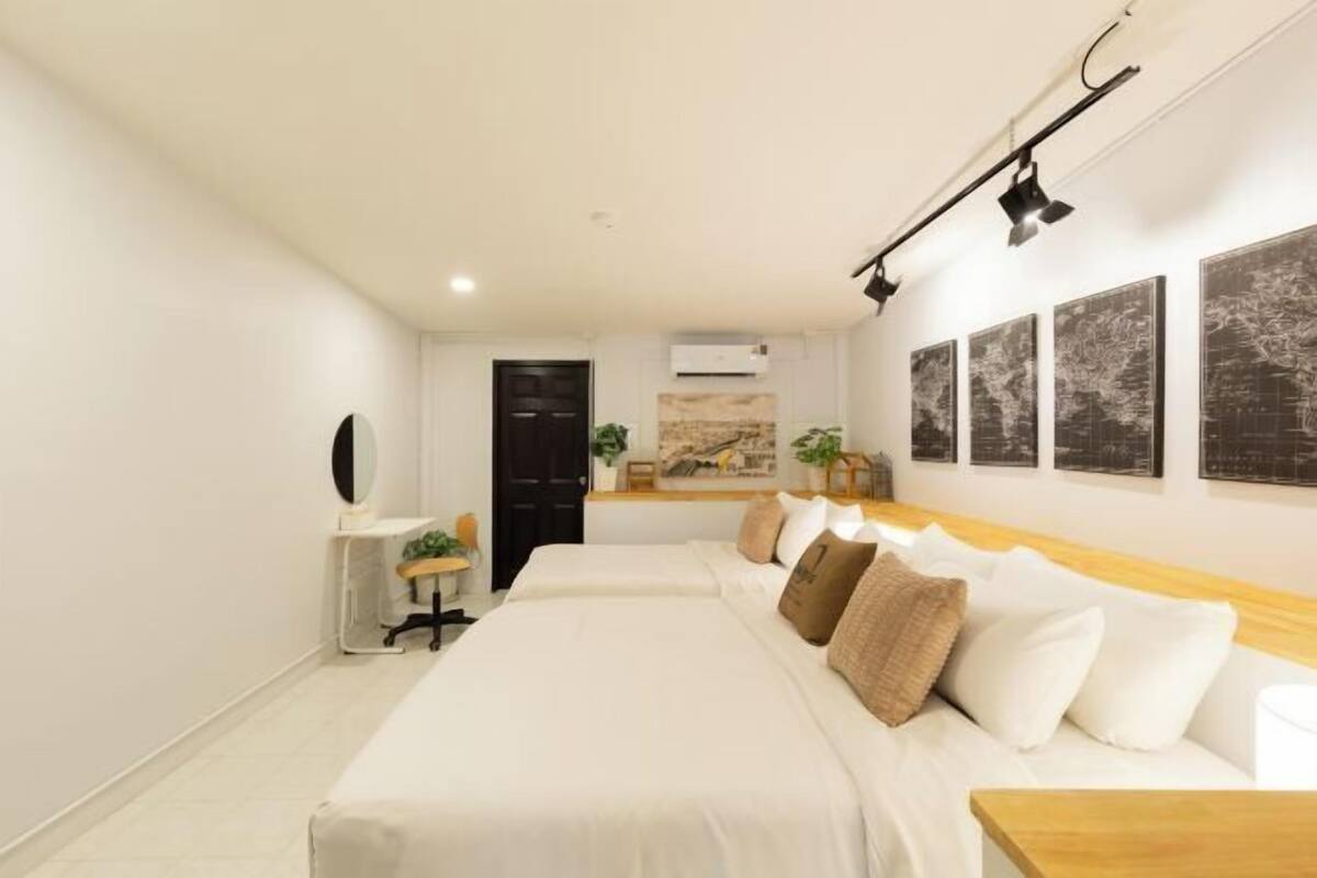 A modern hotel room with a large bed, a desk, and a wall-mounted light fixture.
