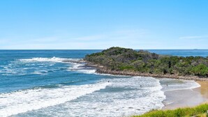 A coastal landscape with a rocky shoreline, waves, and dense vegetation. - Boorolong 4 - Affordable Beachfront Escape with Convent Beach Views - Holiday Yamba (Yamba)