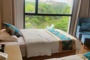 A hotel room with a bed, a chair, and a window with a view of greenery. - Muqing International Hotel (Guilin)