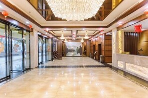 A hotel lobby with a chandelier, glass doors, and a view of a mountain. - Muqing International Hotel (Guilin)