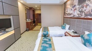 Habitación de hotel con dos camas, un televisor, un cuadro en la pared y un baño visible a través de una puerta abierta.