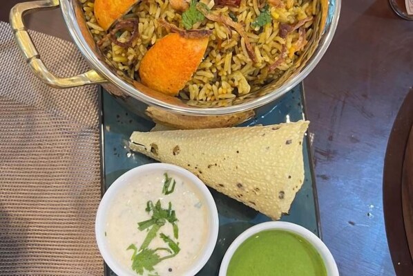 Un plato de arroz, un trozo de pan y dos tazones pequeños de salsa.
