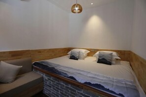 A bedroom with a bed, a wooden headboard, a sofa, and a hanging light fixture. - PingYao DeShengLou Hotel (Pingyao County)