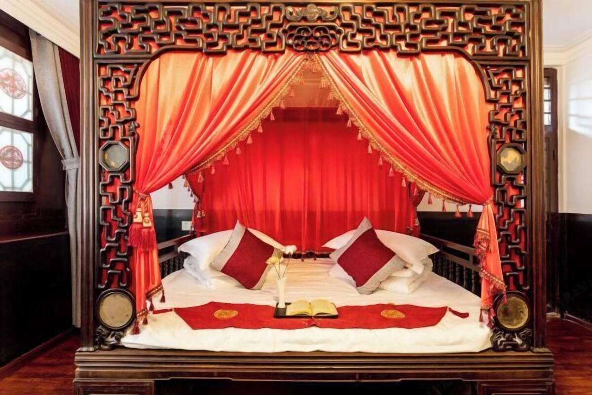Ein traditionelles Bett mit roten Vorhängen und einem Holzgestell.