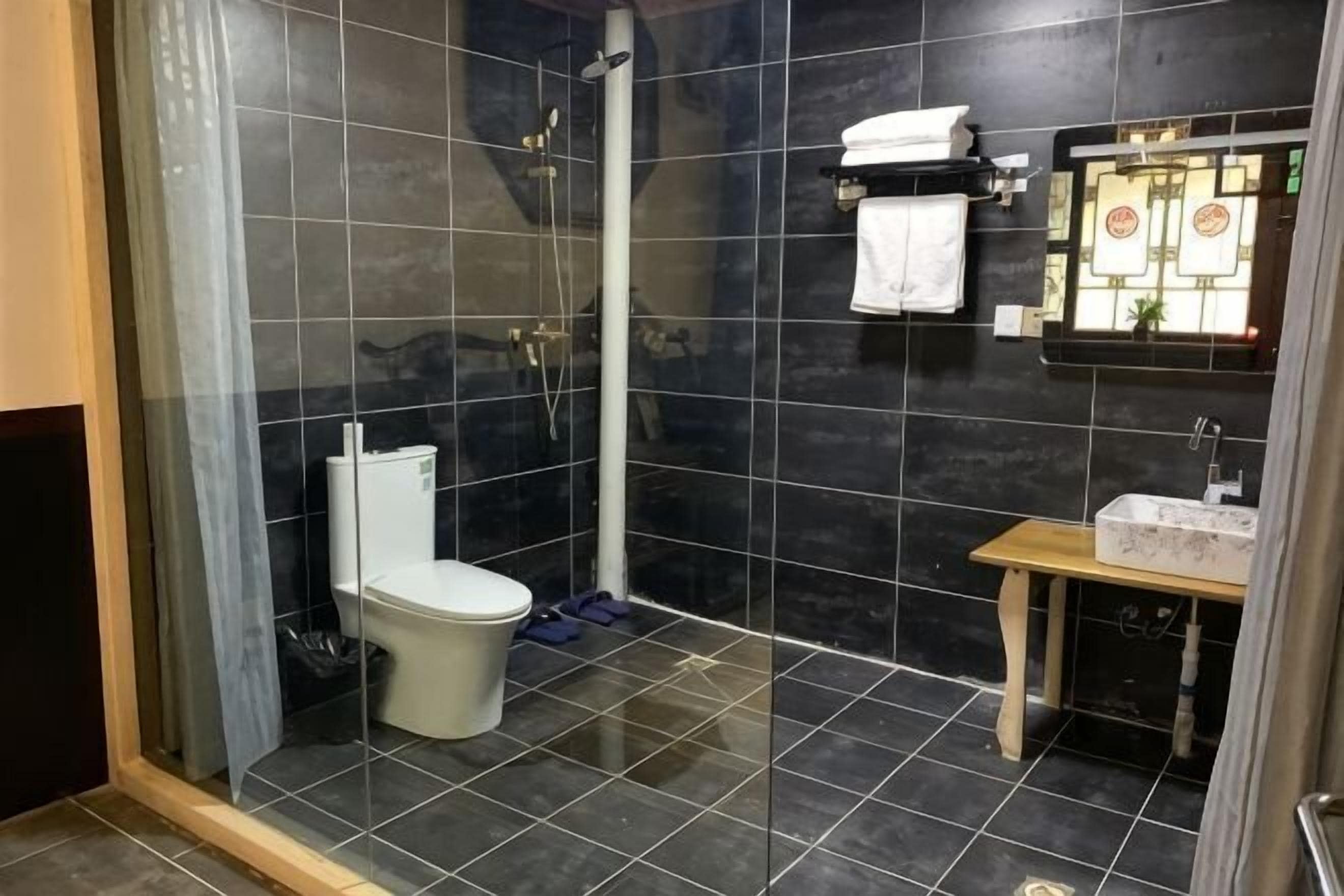 A bathroom with a glass-enclosed shower, a toilet, a sink, and a mirror.