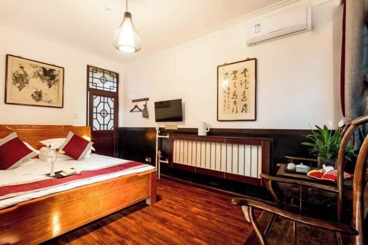 Ein traditionell eingerichtetes Zimmer mit einem hölzernen Bett, einem Fernseher und Bildern an der Wand.