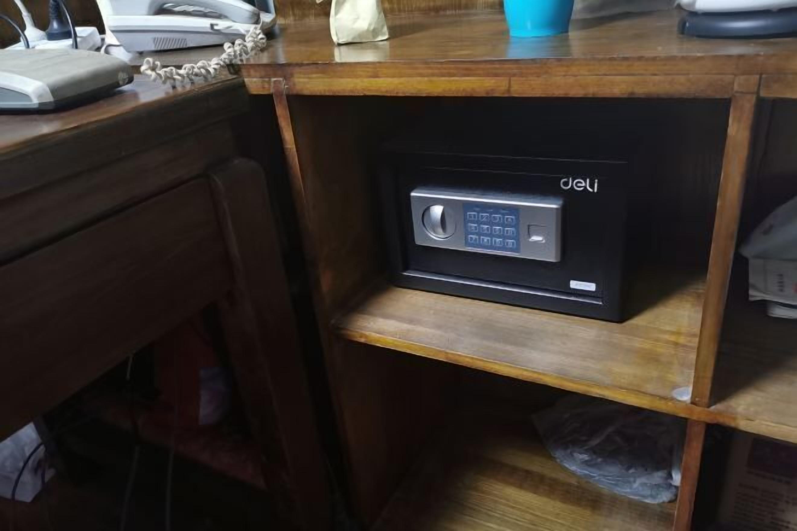A wooden desk with a Dell computer monitor, a telephone, and a blue cup.