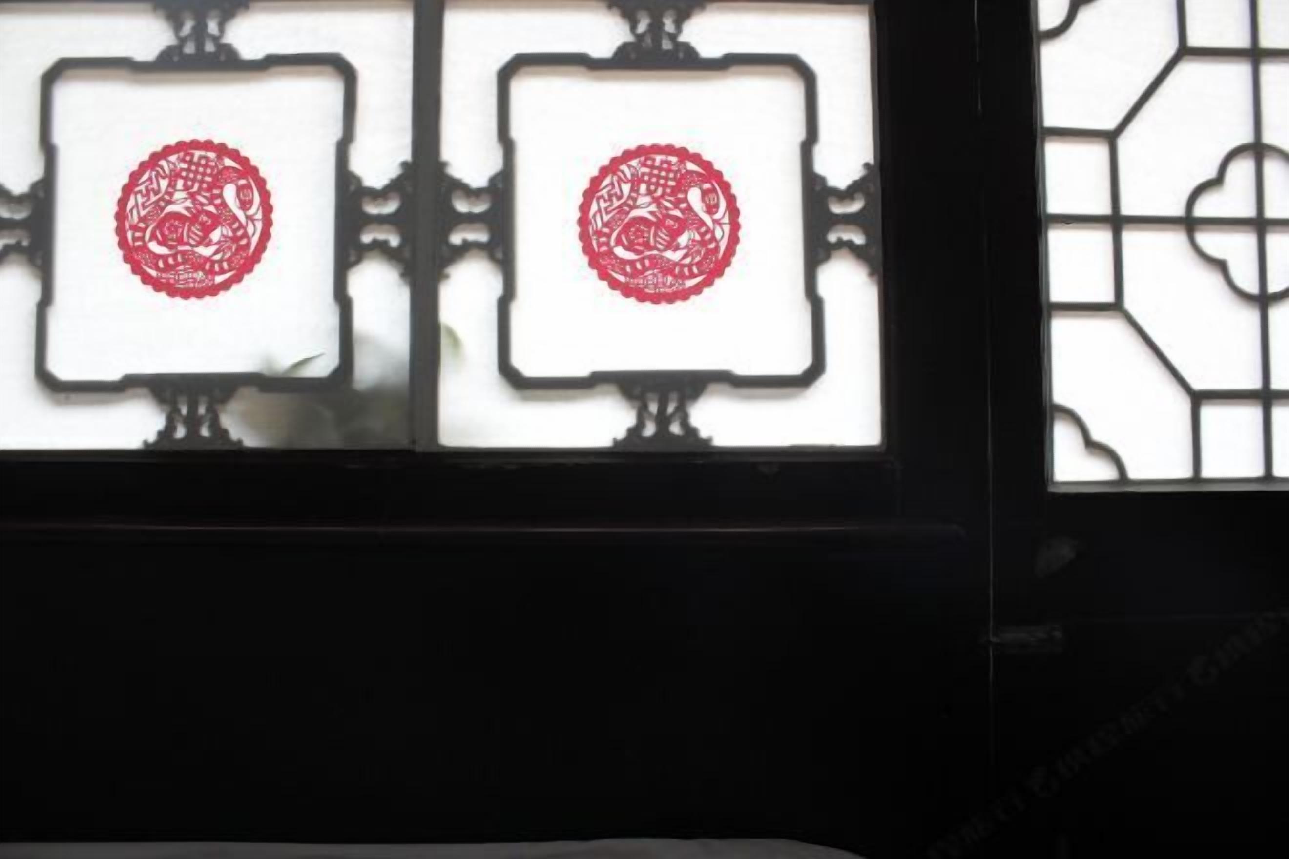 A window with two square panes, each containing a red circular design.