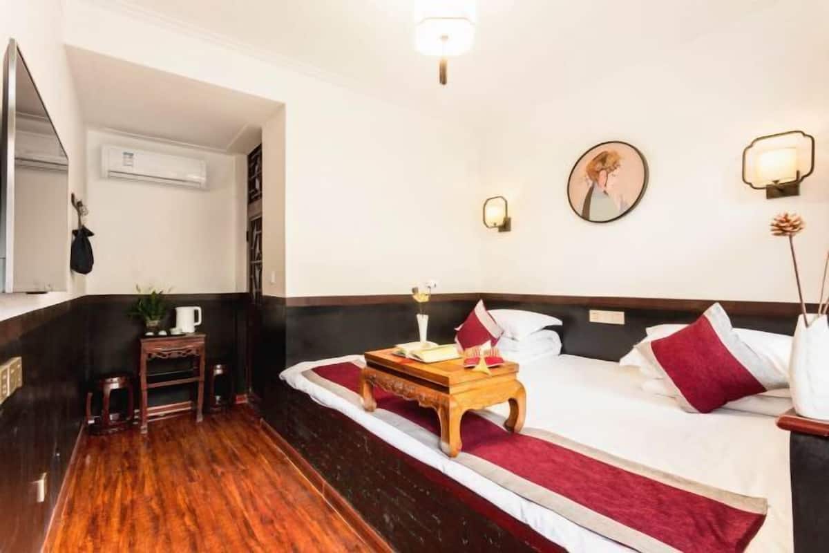 Ein Hotelzimmer mit einem Bett, einem Nachttisch, einem Spiegel und einer Wandklimaanlage.