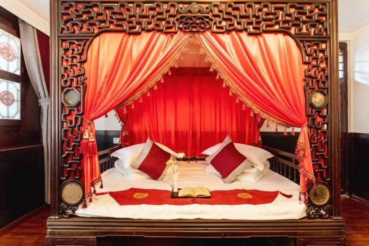 Ein traditionelles Bett mit roten Vorhängen und einem verzierten Kopfteil.