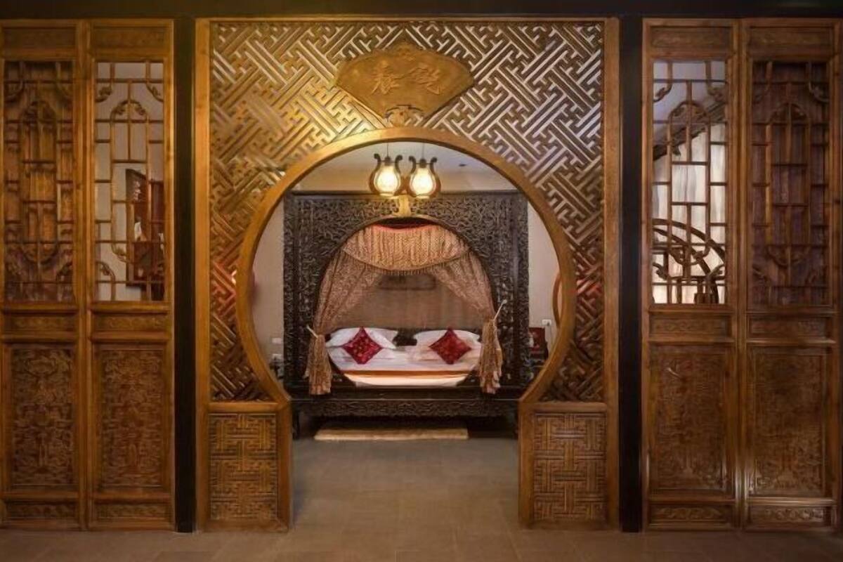 Ein traditionell eingerichteter Raum mit einem verzierten Bett, einer dekorativen Decke und aufwendigen Holzvertäfelungen.