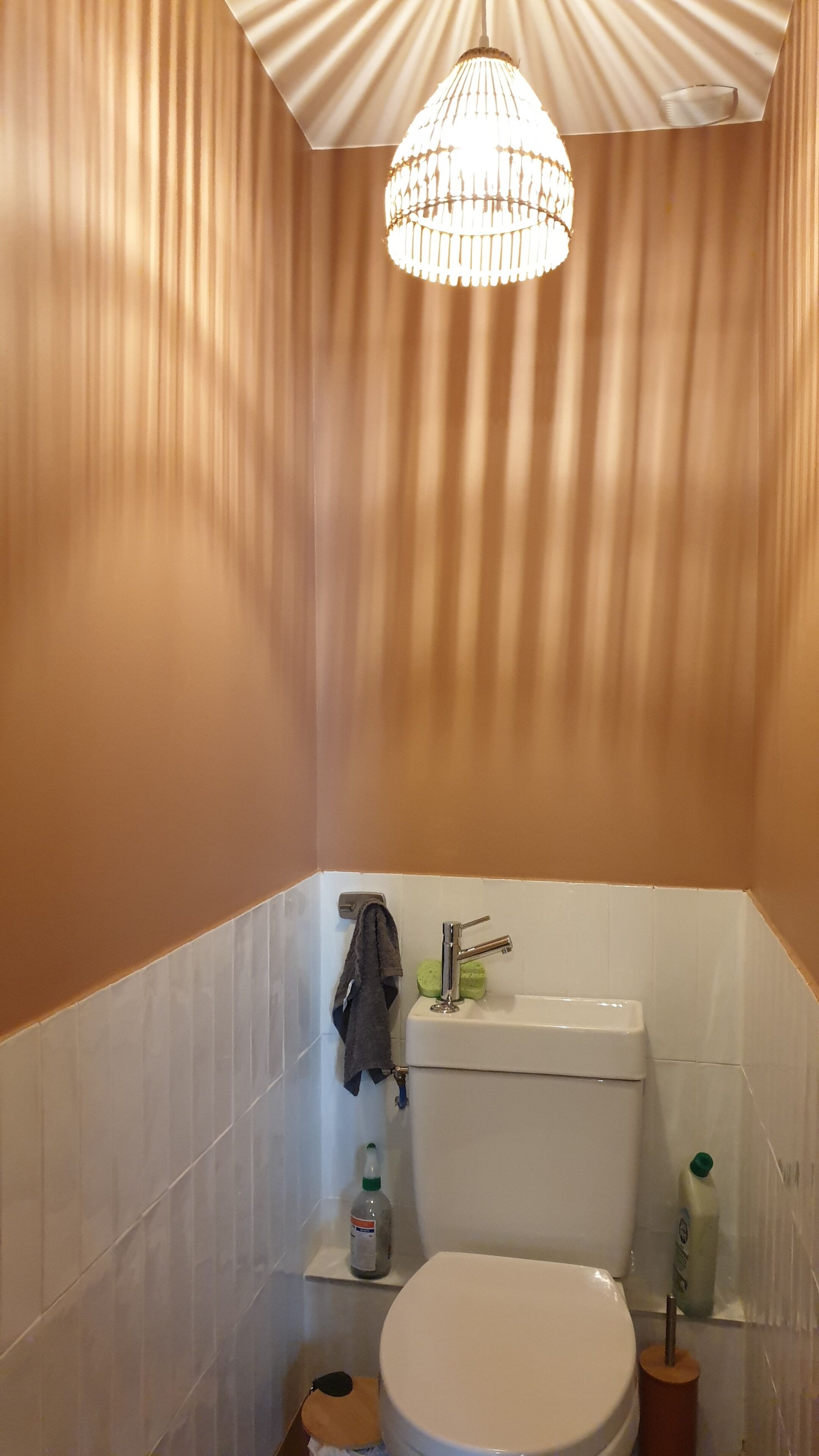 A bathroom with a white toilet, a sink with a faucet, a towel hanging on the wall, and a shower curtain.