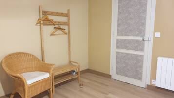 A room with a wicker chair, a wooden bench, a coat rack, and a patterned door.