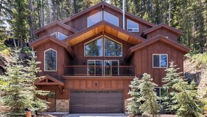 Ein modernes Holzhaus mit großer Garage, umgeben von Bäumen.
